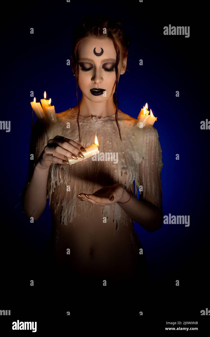 Seductive sorceress dripping wax from burning candle Stock Photo