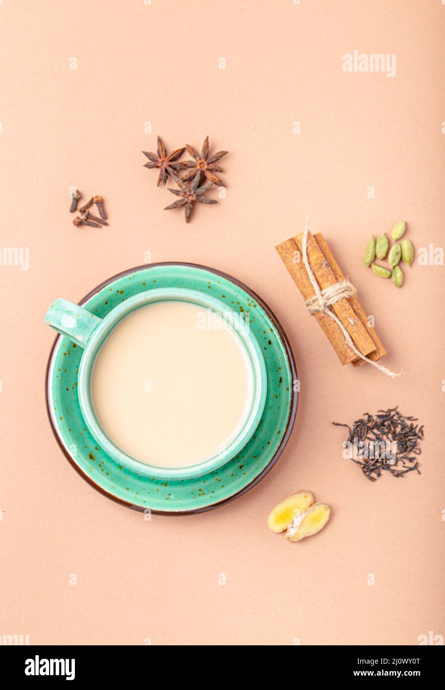 Indian tea drink with milk and spices in rustic green teacup with ingredients for making masala chai Stock Photo