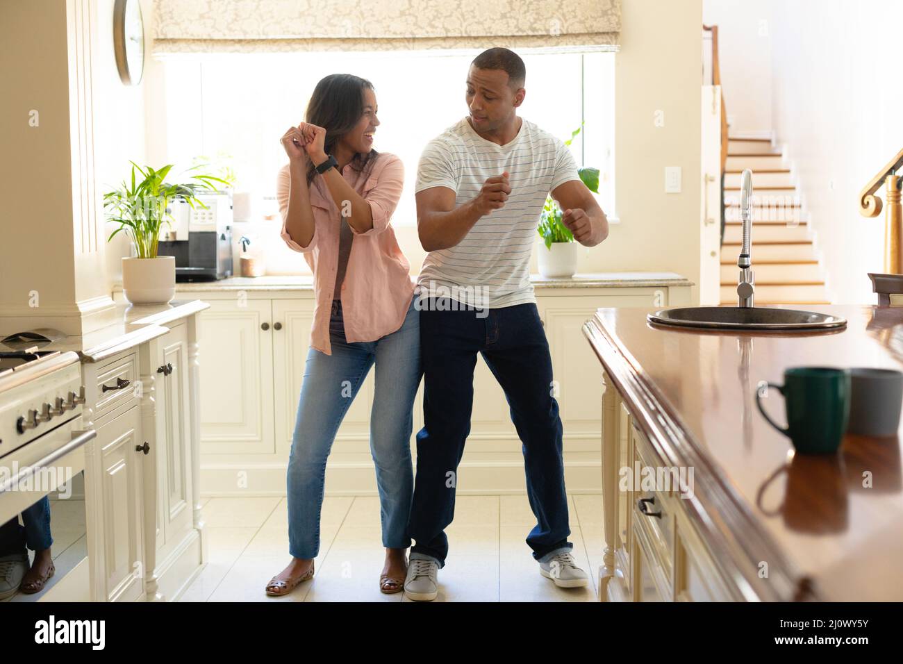 Cheerful young african american couple dancing together in kitchen at ...