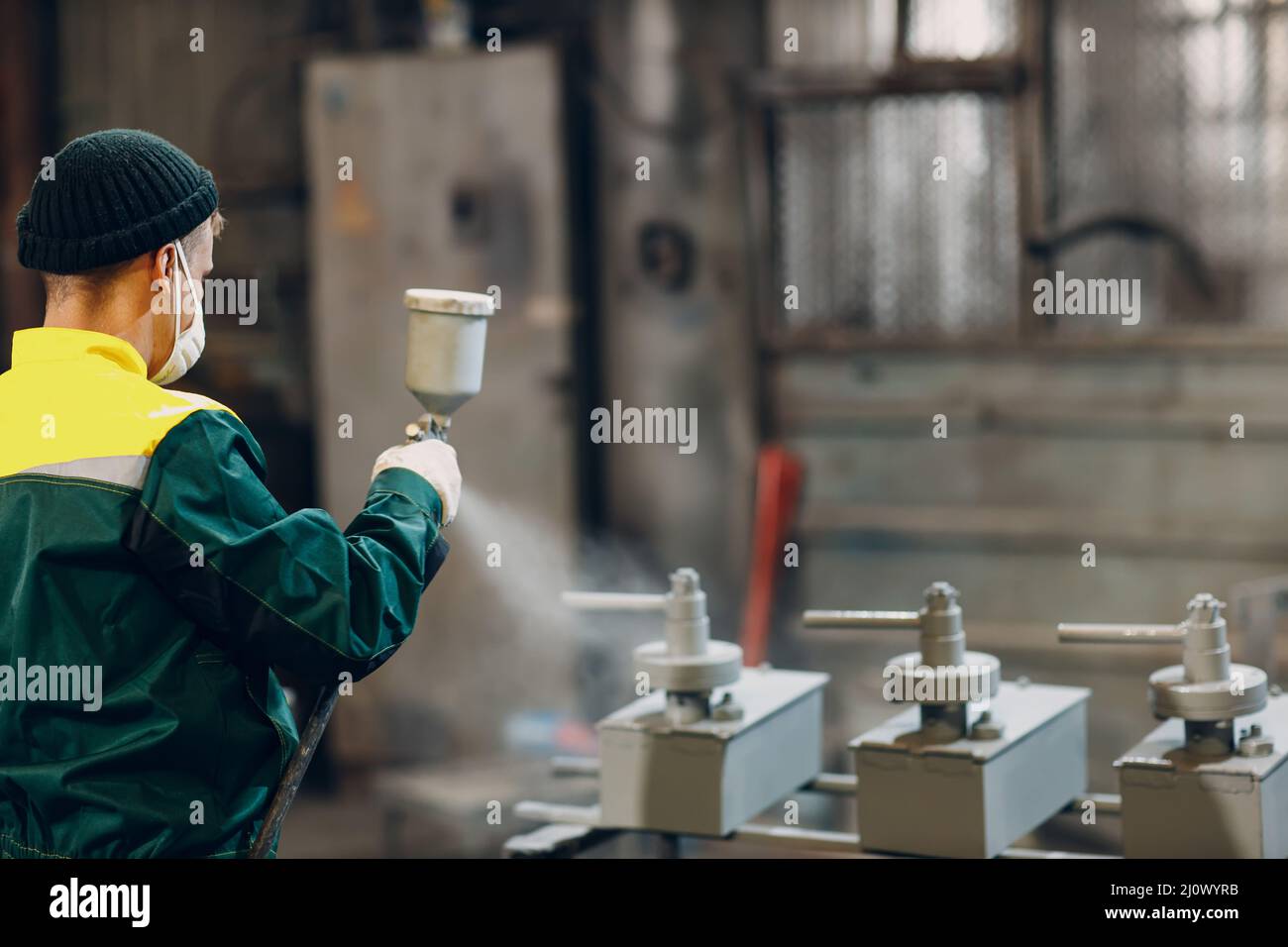 Powder primer coating of metal parts. Worker man in a protective suit