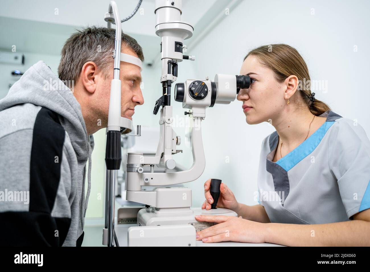 Doctor and patient in ophthalmology clinic. Male patient checking vision with special eye equipment. Optometry concept. Man visi Stock Photo