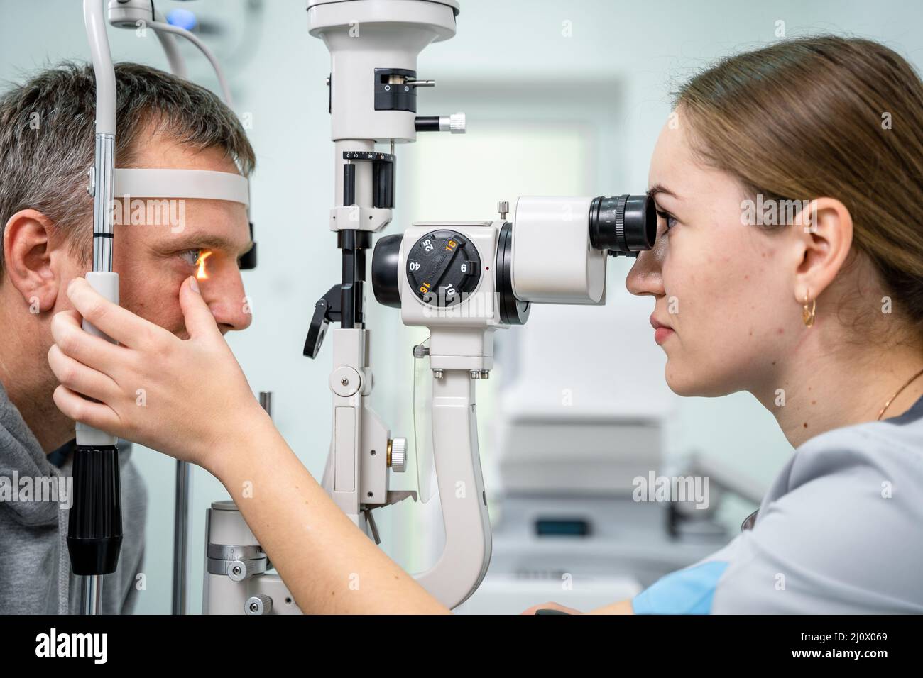 Ophthalmologist and patient testing eyesight. Man doing eye test with optometrist. Ophthalmologist using apparatus for eye exami Stock Photo