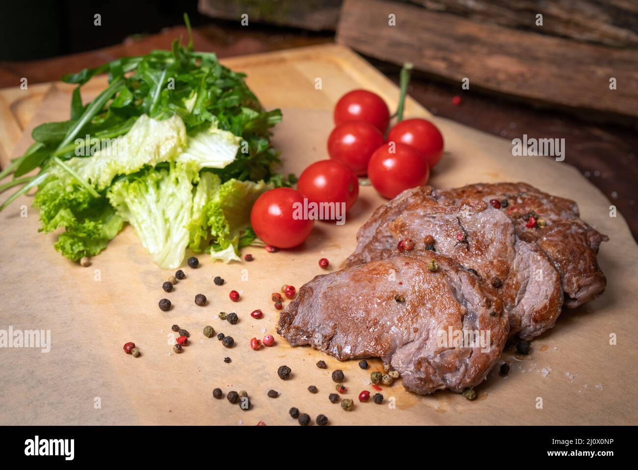 Pork fillets are served with barbecue sauce, soy sauce, cherry tomatoes, lettuce salad with arugula-seeded pepper mixture. Resta Stock Photo
