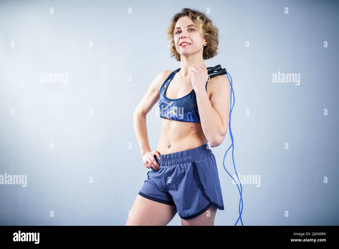 Fit woman with jump rope posing in the gym. Sport exercises healthy lifestyle concept. Sporty happy woman with skipping rope pos Stock Photo