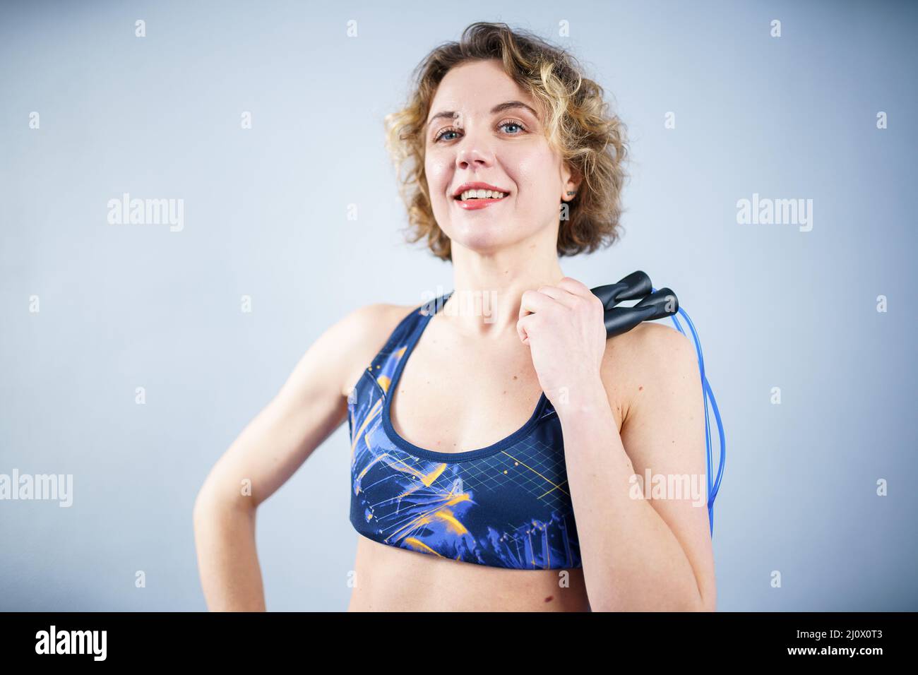Smiling sportswoman posing with a skipping rope. Female with muscular body posing with jump rope. Fitness model. Body positivity Stock Photo
