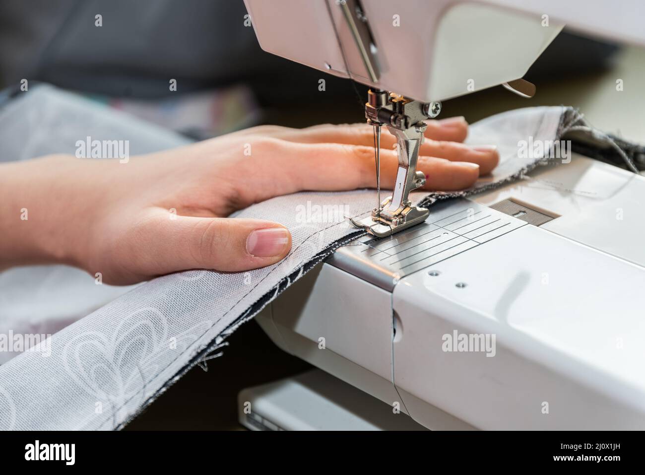 Woman sews with a sewing machine - seamstress in tailor shop Stock Photo