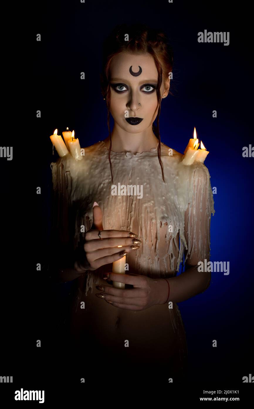 Sensual lady with witch makeup and burning candles Stock Photo