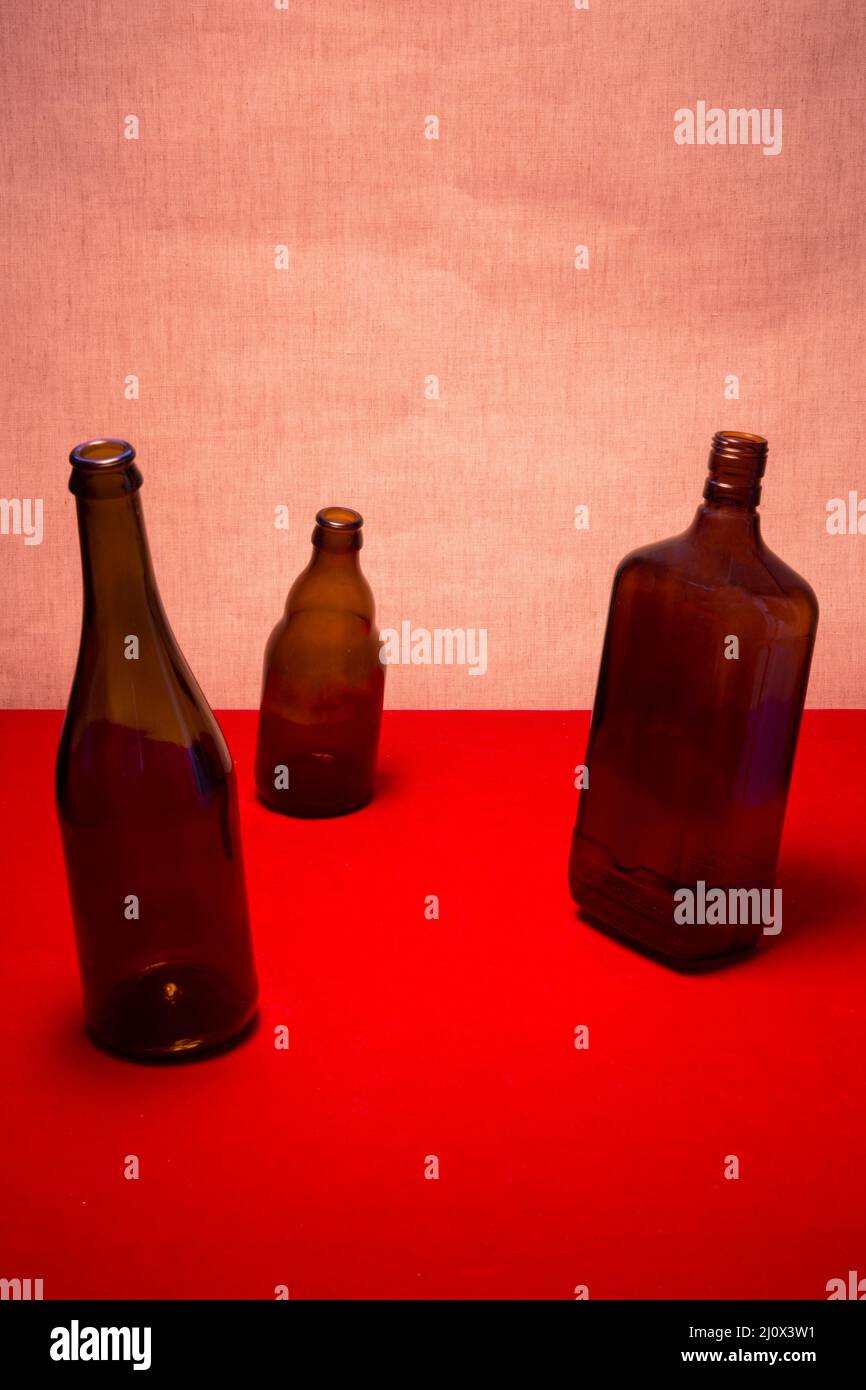 Still life with tilted bottles on a red table Stock Photo Alamy