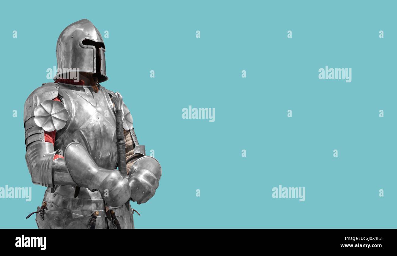 Medieval knight in shiny metal armor on a blue background. Stock Photo