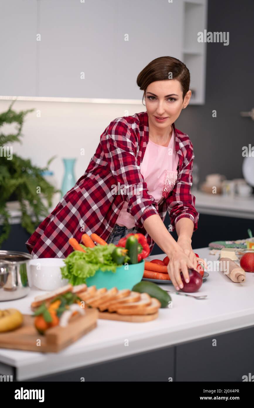 Beautiful woman with short hair and red shirt makes fresh food at home. Healthy lifestyle concept portrait of a beautiful young Stock Photo