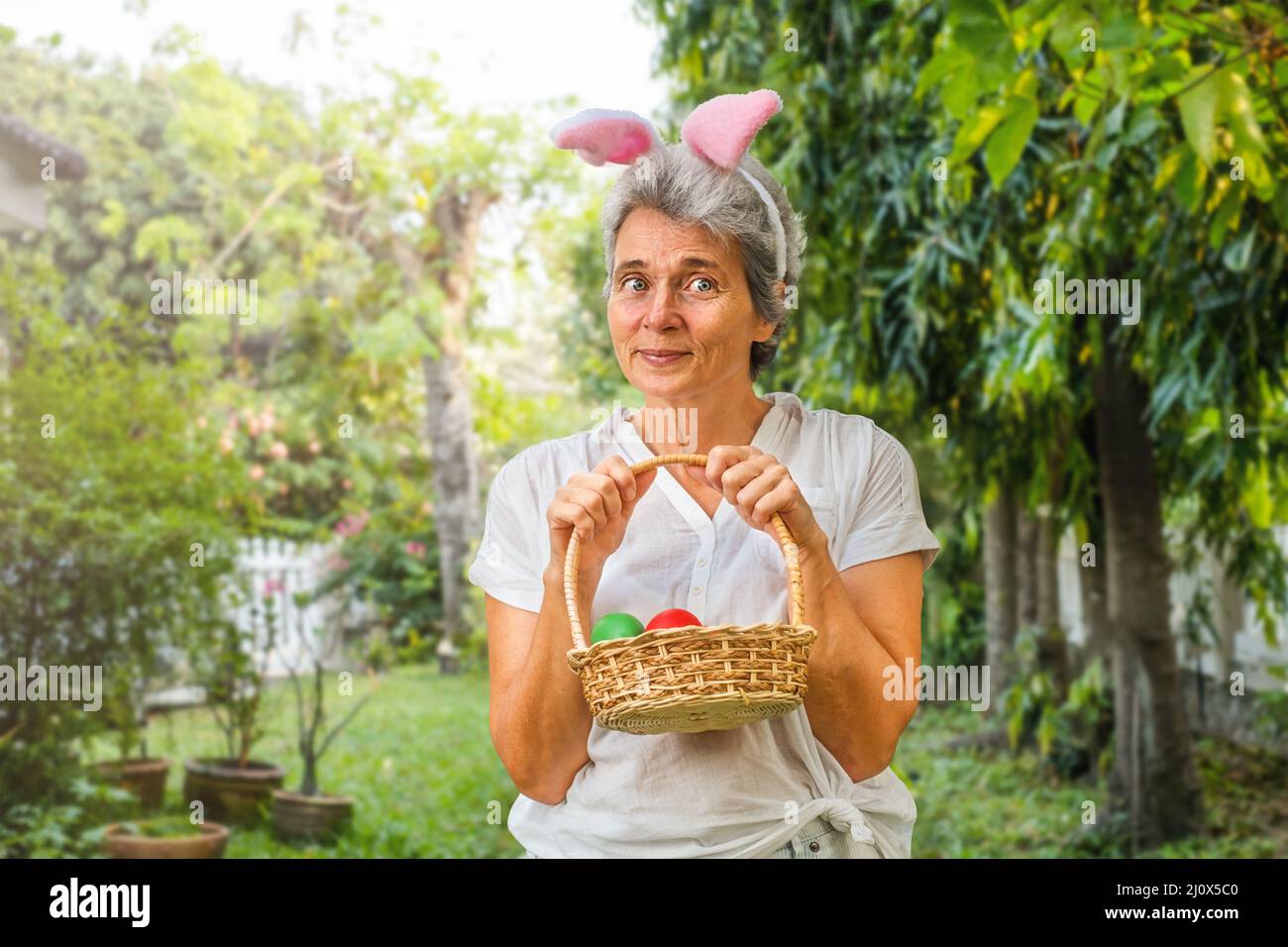 Happy senior woman with easter eggs in basket outdoor Stock Photo