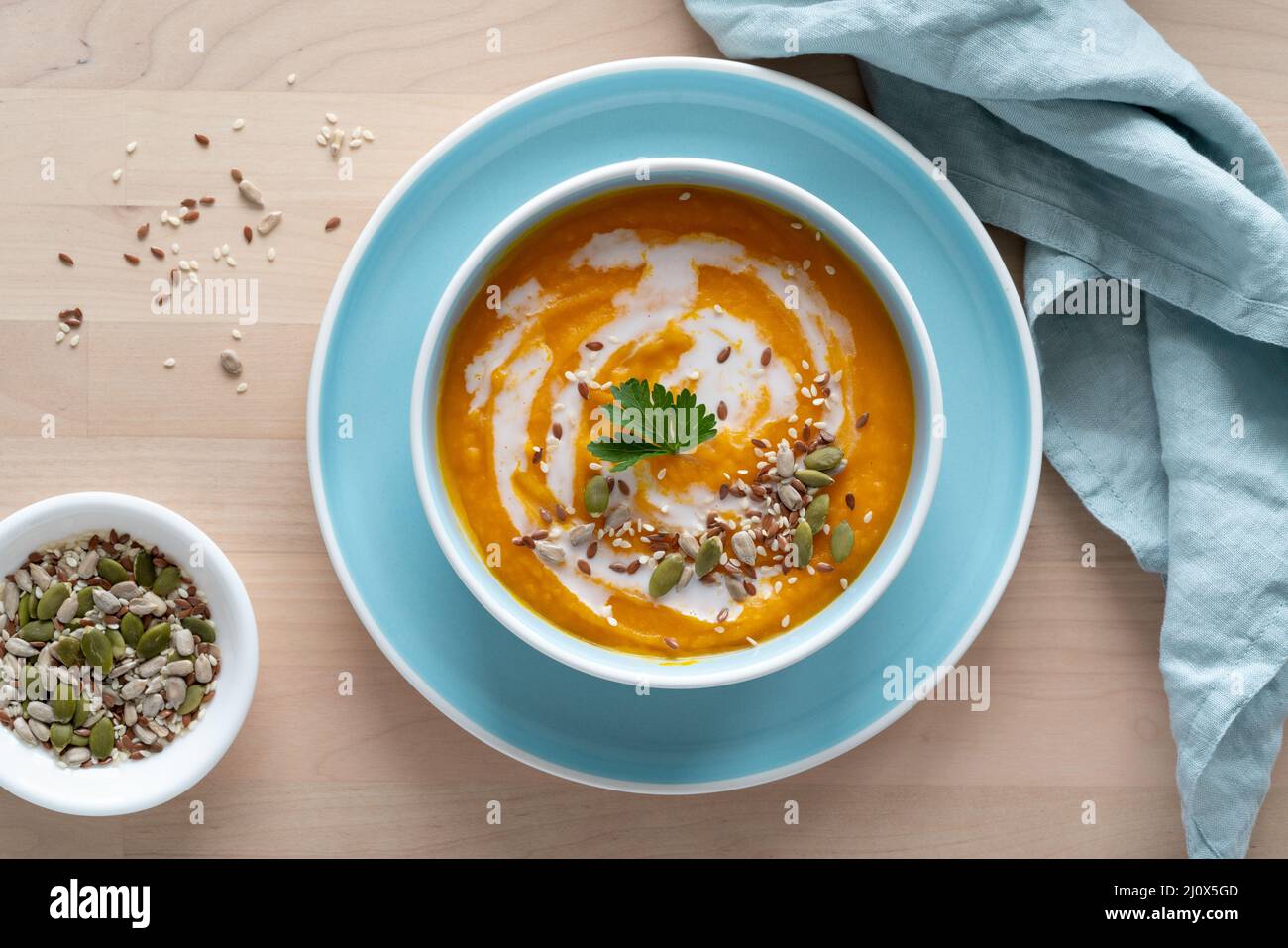 Pumpkin soup with coconut milk and seeds in blue bowl, top view, copy space Stock Photo