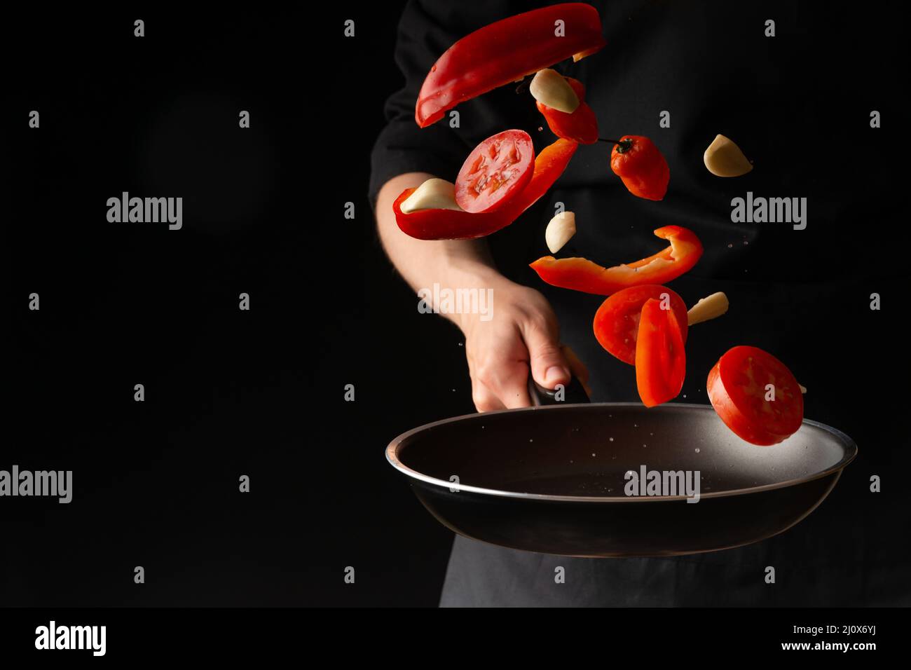 Chef prepares vegetables, roasting on a griddle on a black background, horizontal photo, menu, recipe book, restaurants, healthy and tasty food Stock Photo