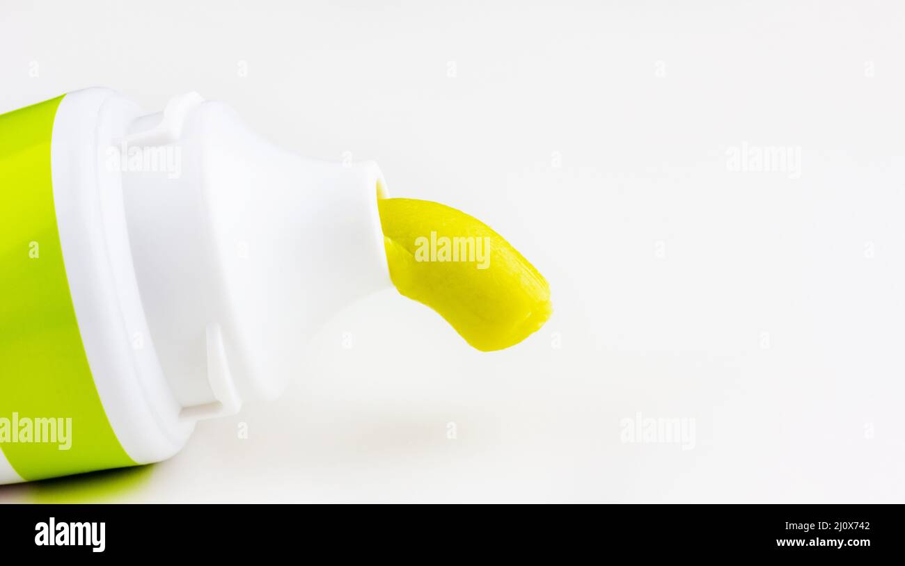 Green toothpaste is squeezed out of a tube of toothpaste closeup on a white background with a