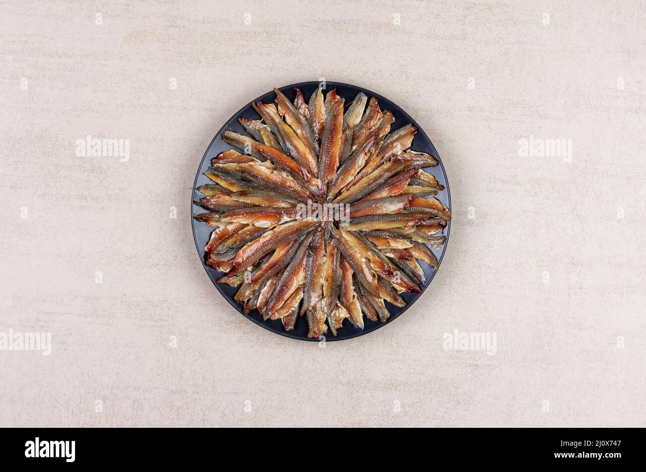 European anchovy fish fillet in a black plate on a gray background top view Stock Photo