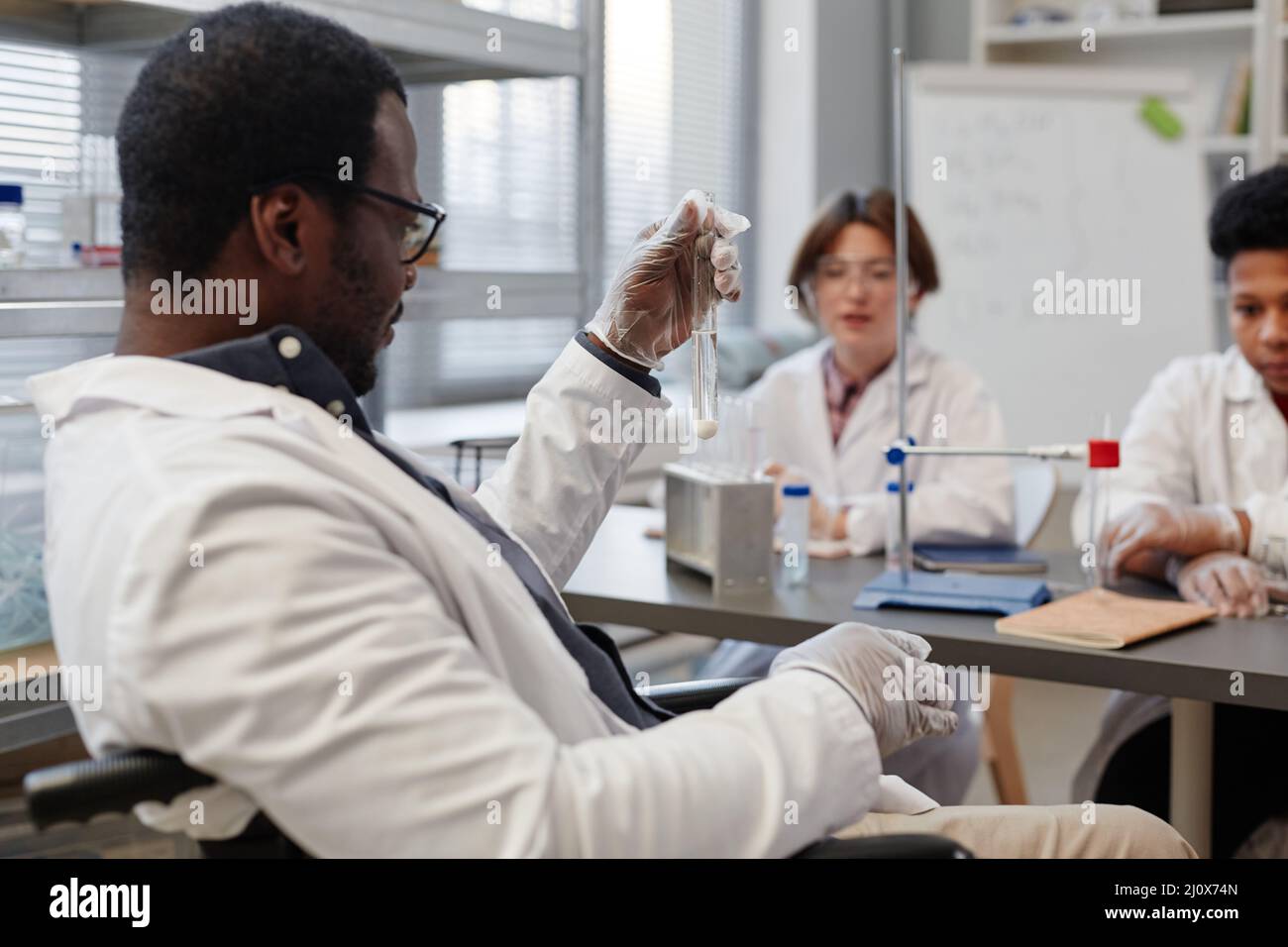 Side view of African American science teacher holding test tube while ...