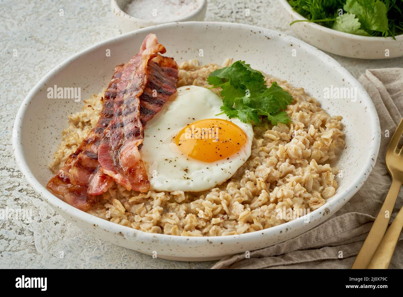 Oatmeal, fried egg, fried bacon. Hearty fat high-calorie breakfast. Balance of proteins, fats, carbohydrates, side view Stock Photo