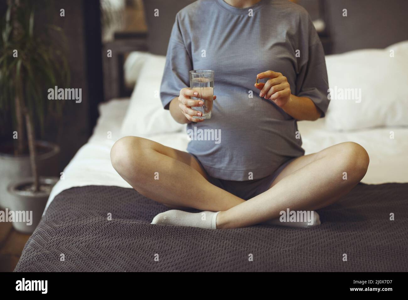 Pregnant woman taking prenatal vitamins during pregnancy, holding water