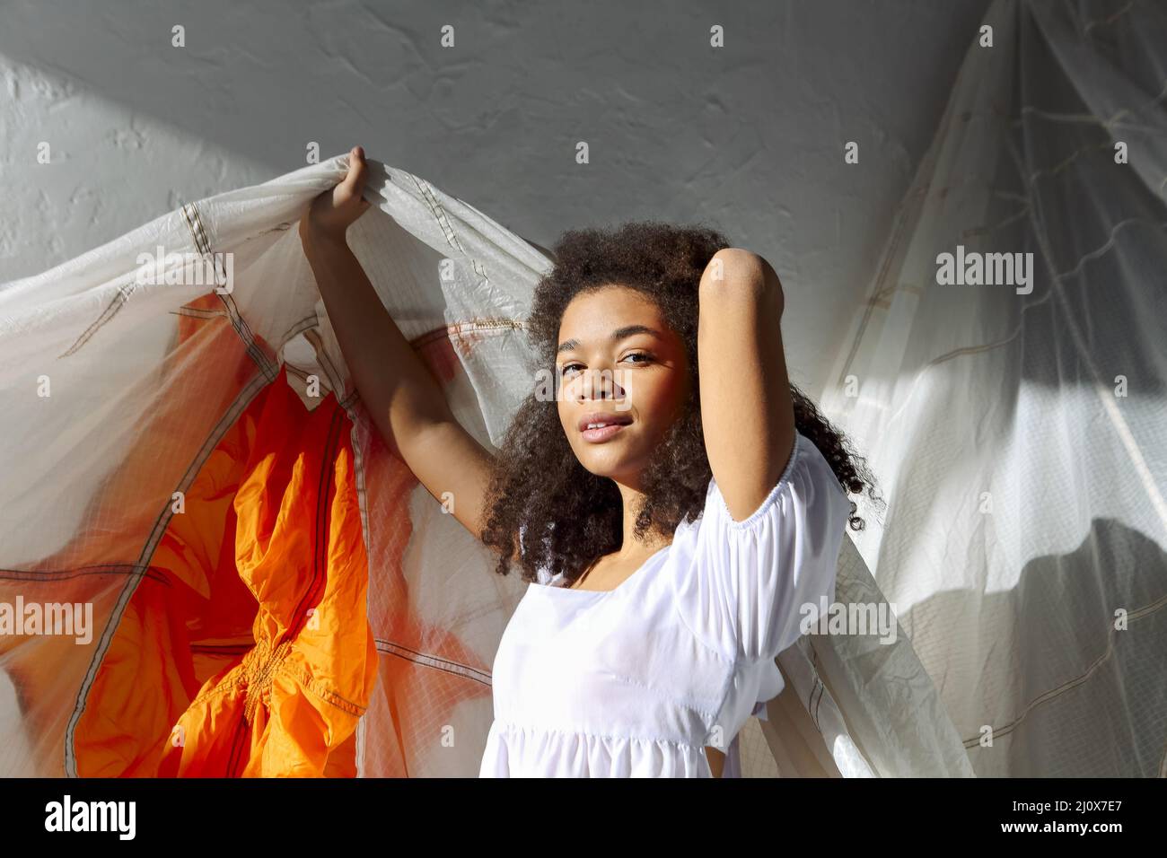 Overjoyed happy african american woman jumping with white fabric in air ...