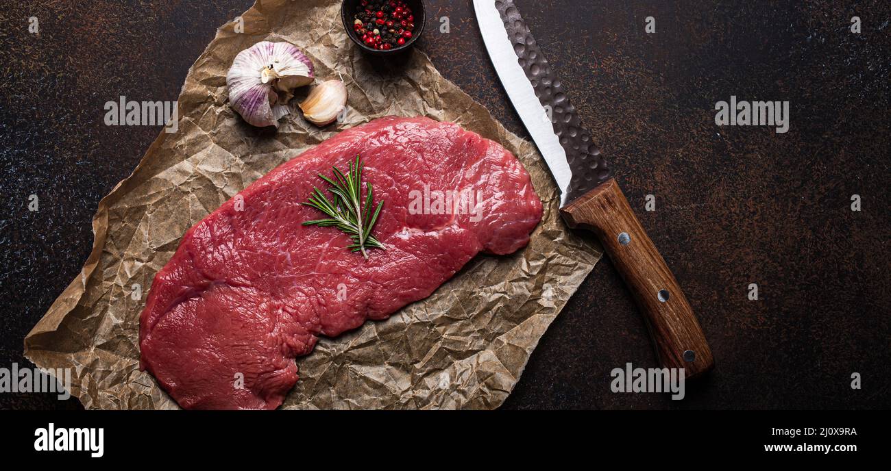 Beef lean raw fillet steak on baking paper with rosemary, garlic and spices Stock Photo