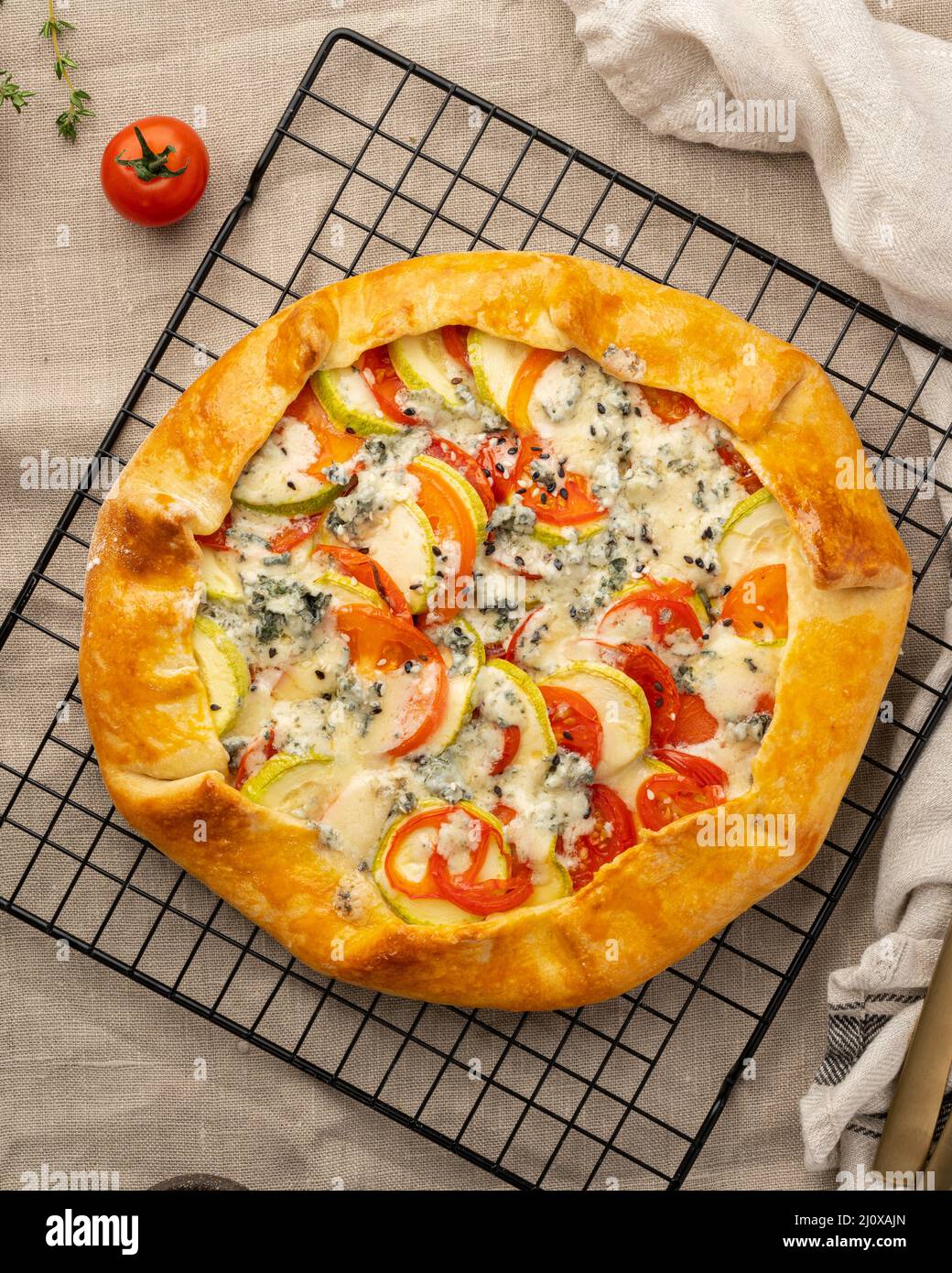 Homemade savory galette with vegetables, wheat pie with tomatoes, zucchini, vertical Stock Photo