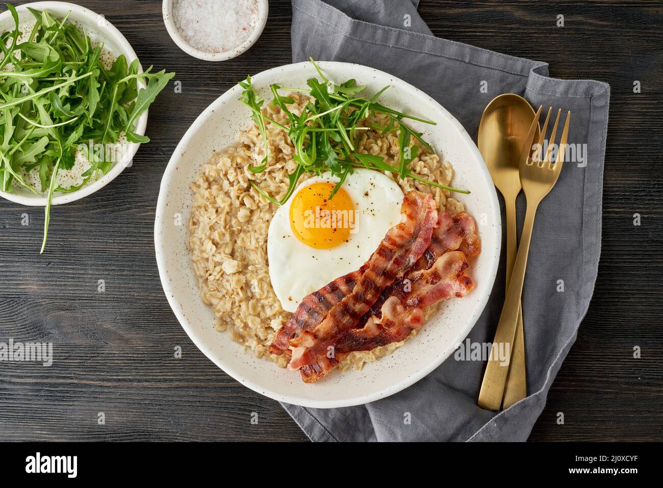 Oatmeal, fried egg and fried bacon. Balance of proteins, fats, carbohydrates. Close up Stock Photo