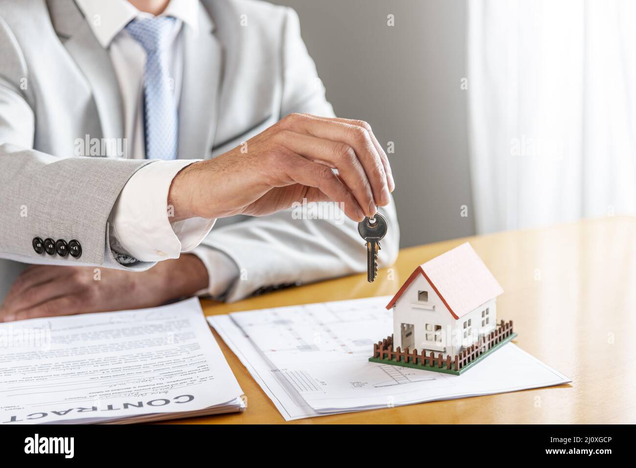 Person holding house keys toy model house desk. High quality beautiful photo concept Stock Photo