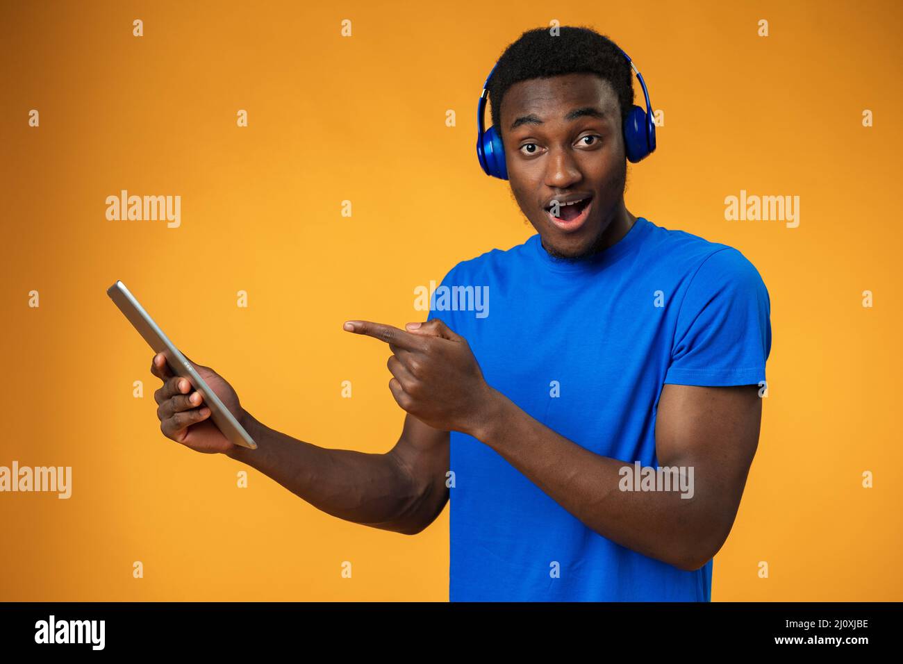 Smiling african guy using digital tablet over yellow background Stock Photo