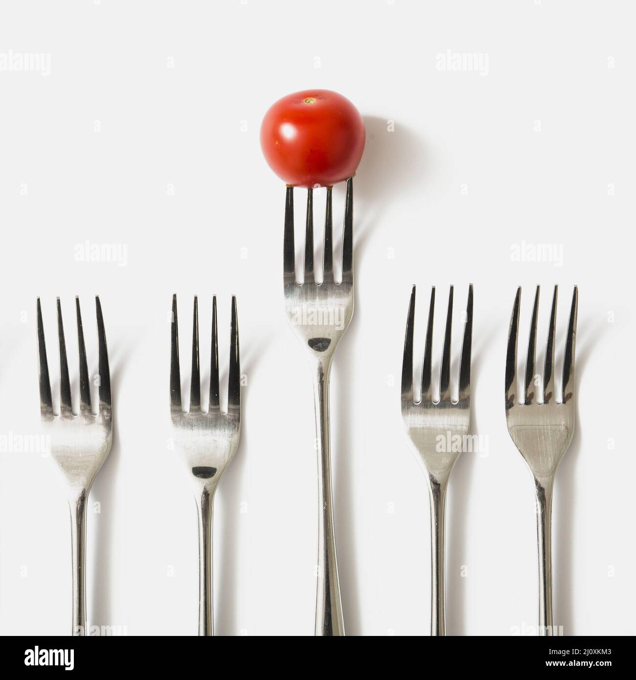 Red cherry tomato fork against white background Stock Photo