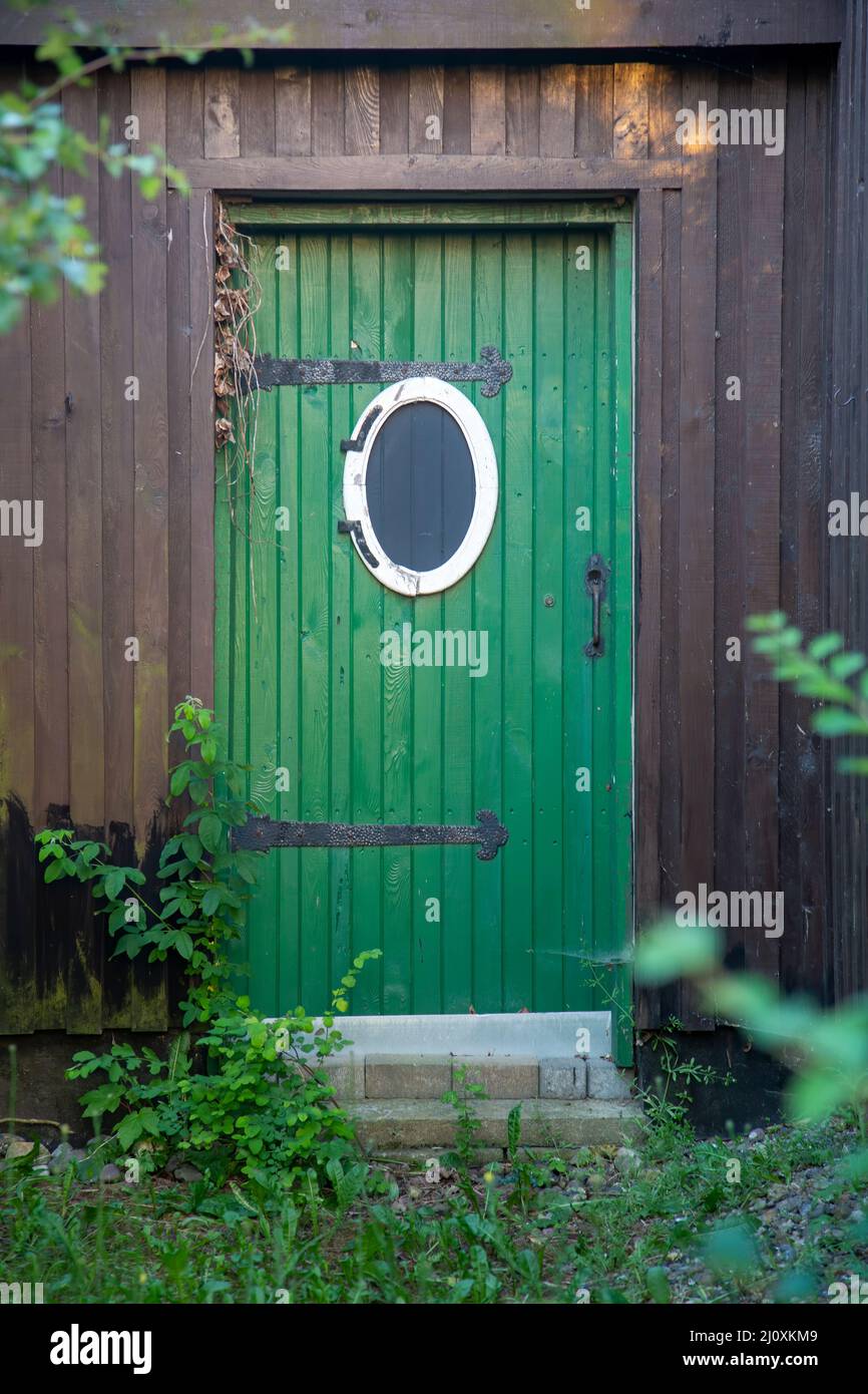 Old green wooden door with a bullseye window Stock Photo