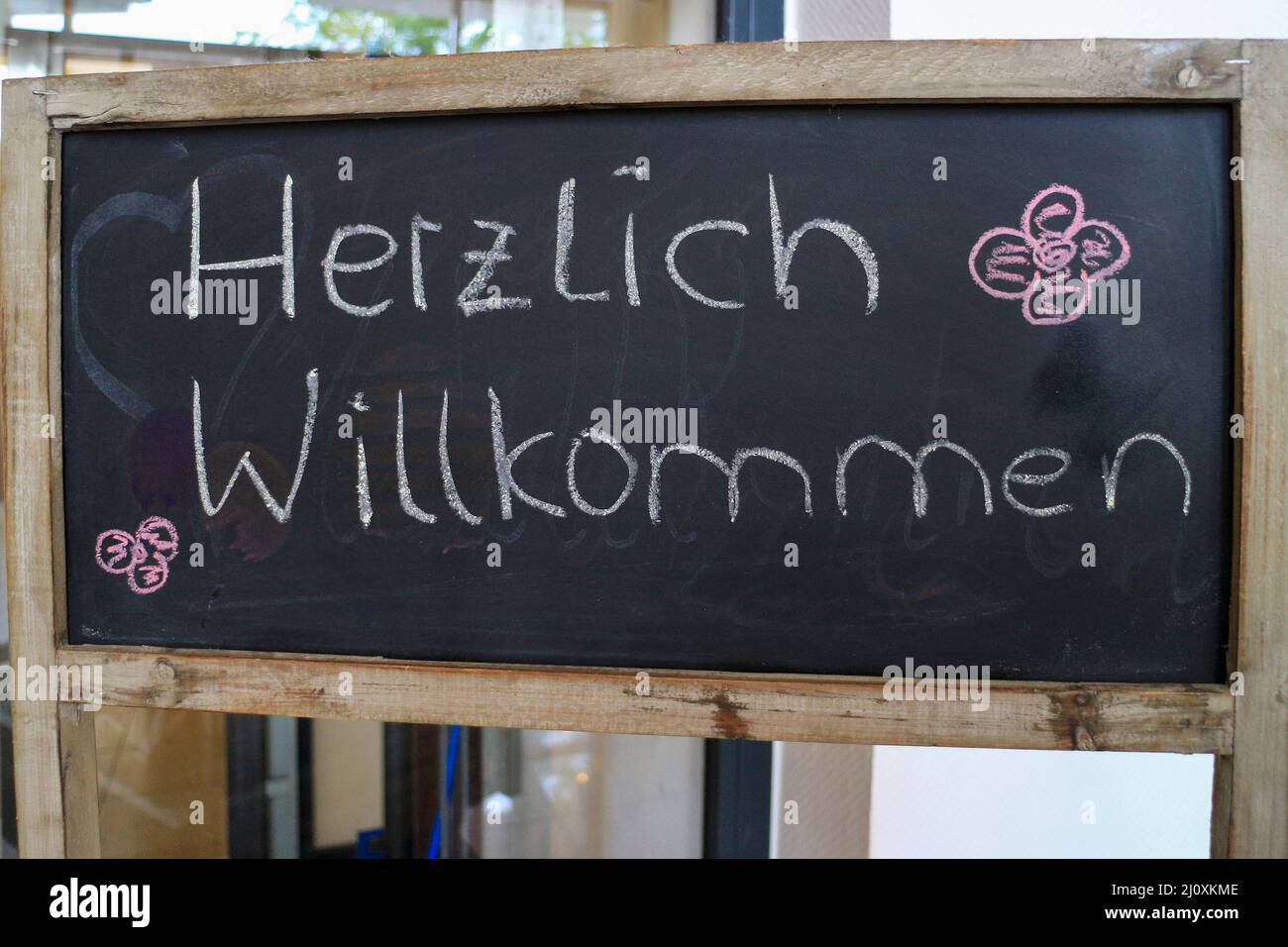 Outdoor blackboard with the German text 'Herzlich willkommen' which translates into 'Heartly welcome' in English language Stock Photo