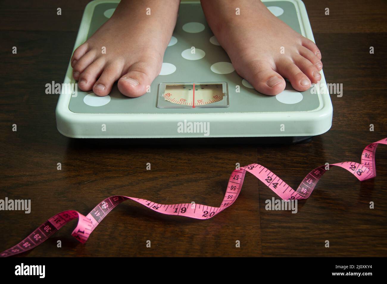 Straight view of measuring tape and feet on weight scale . Weight loss and fitness concept. Stock Photo