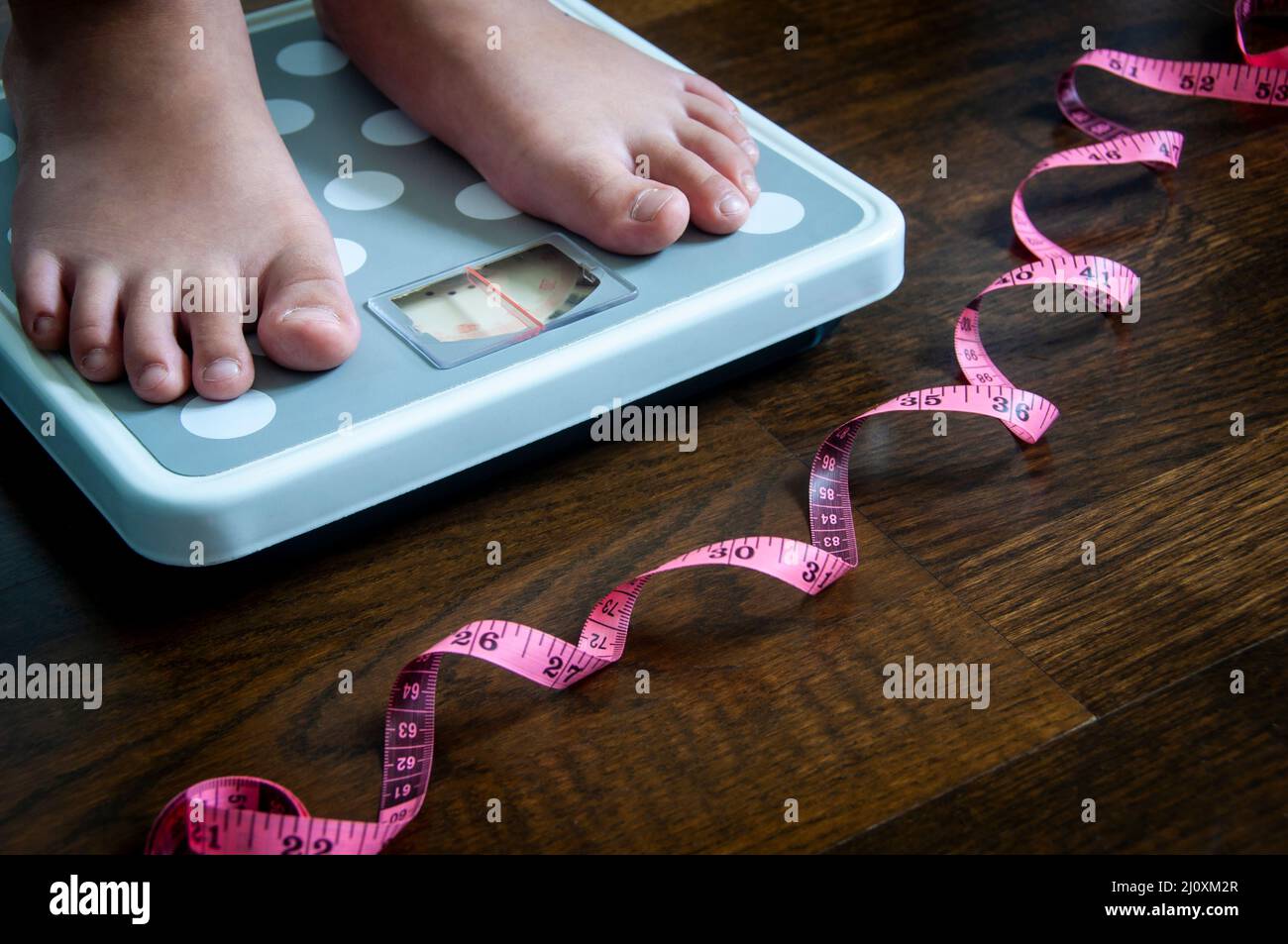 Side view of measuring tape and feet on weight scale . Weight loss and fitness concept. Stock Photo