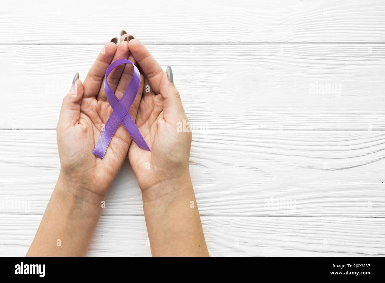 Hands with violet ribbon wooden background. High quality beautiful photo concept Stock Photo