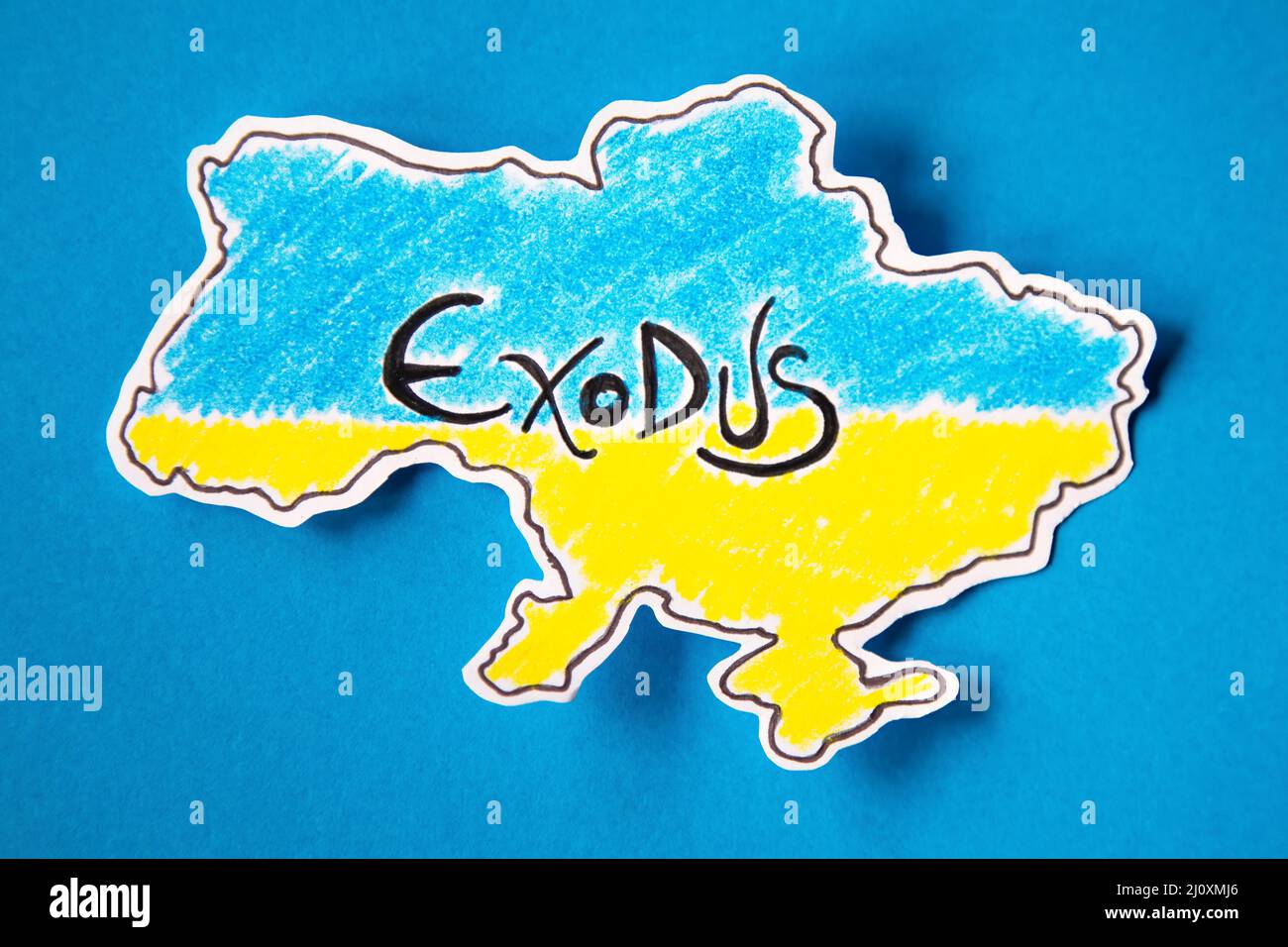 paper cut out in the shape of the territory of ukraine painted with the colors of its flag in representation of mass exodus. blue background with spac Stock Photo
