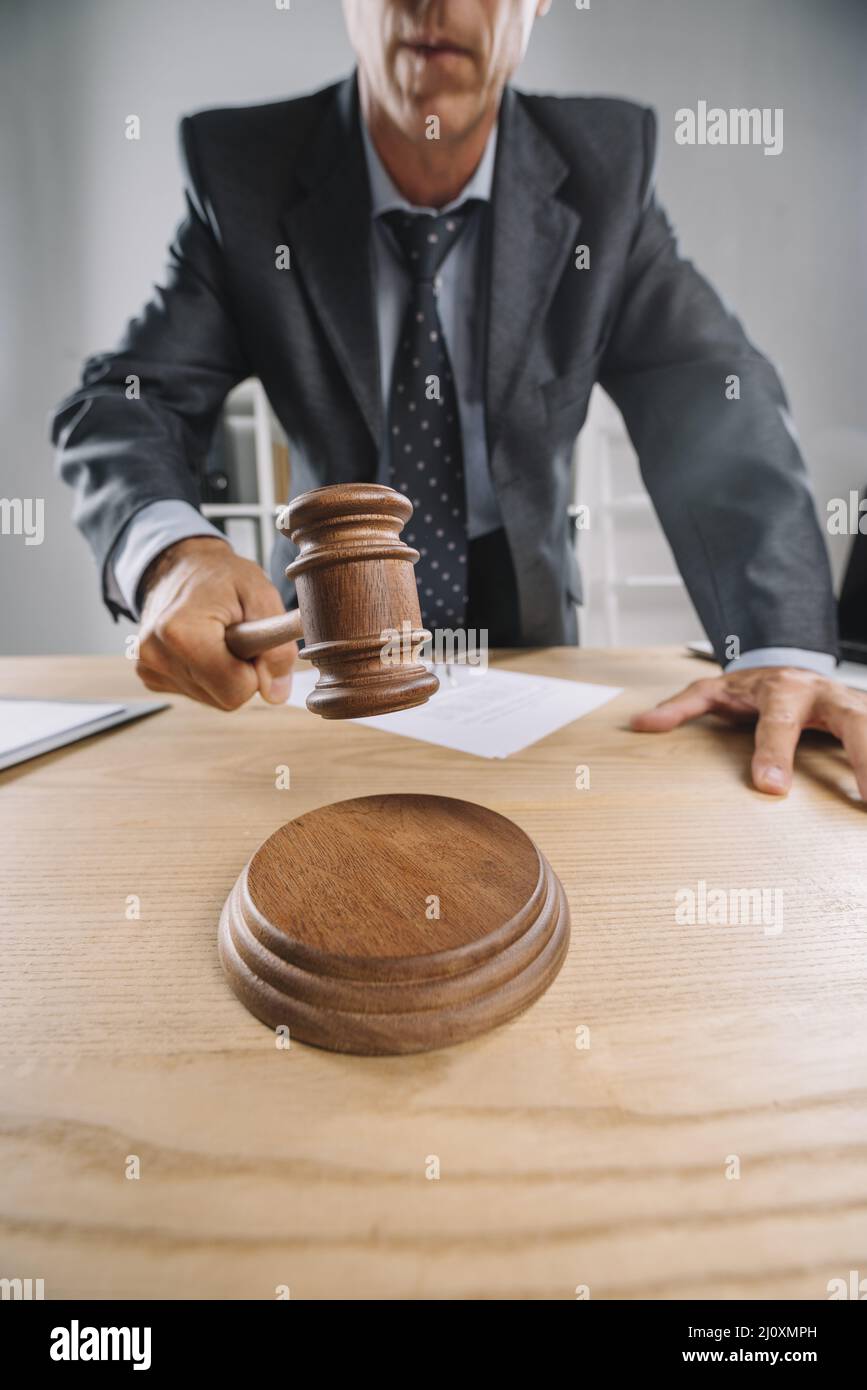 Close up male judge giving verdict by hitting gavel desk Stock Photo