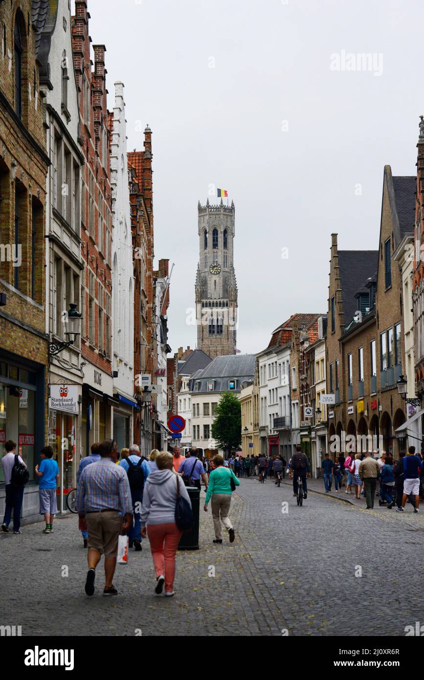 Walking along Steenstraat with the Belfry of Bruges in front. Stock Photo