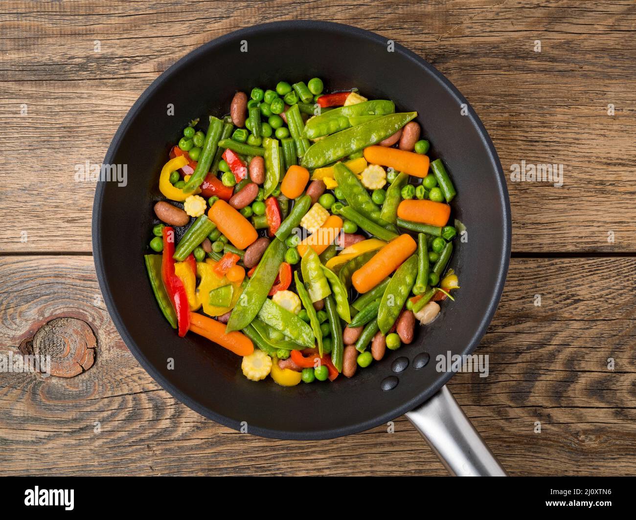 Big pan fried with colorful vegetables - peppers, peas, green beans, baby corn, carrots, beans. Colorful vegetarian lunch, top v Stock Photo