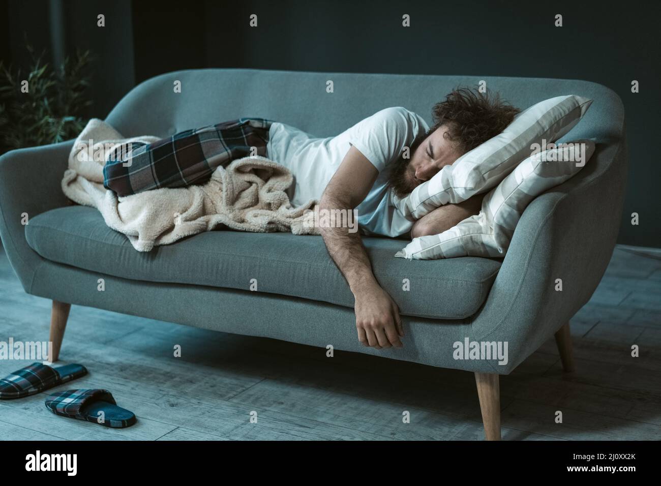 Crashed out sleeping handsome man fell asleep watching tv mid day resting on the couch or sofa enjoying weekend or quarantine da Stock Photo