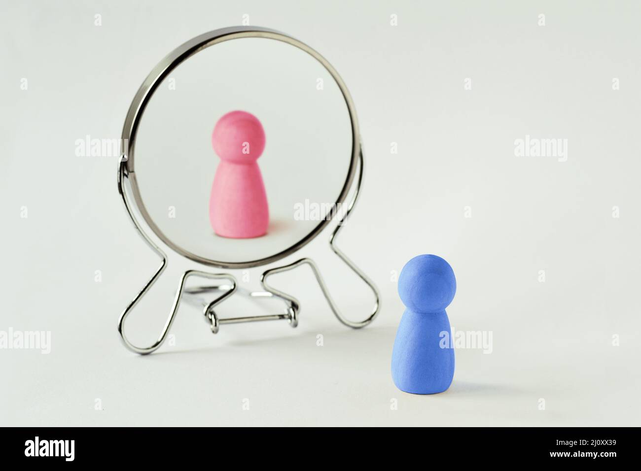 Blue pawn looking in the mirror and seeing himself pink - Gender identity concept Stock Photo