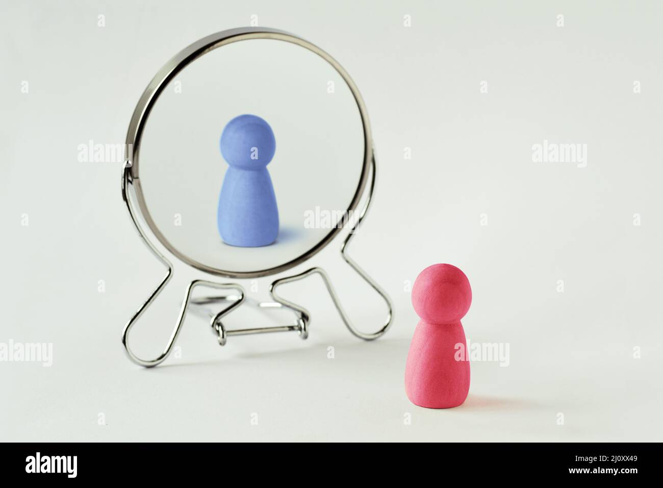 Pink pawn looking in the mirror and seeing himself blue - Gender identity concept Stock Photo