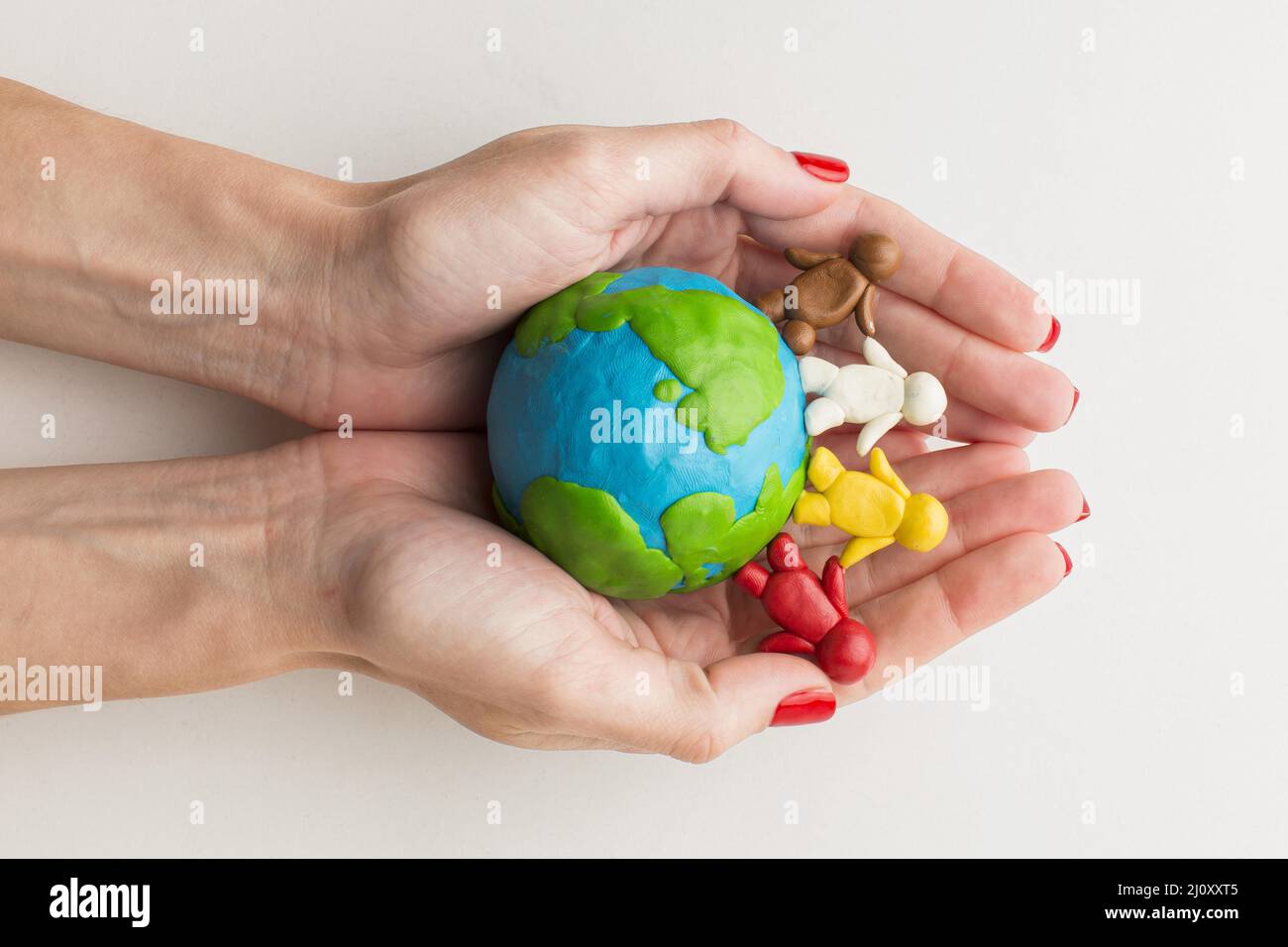 Top view hands holding plasticine globe people. High quality photo Stock Photo