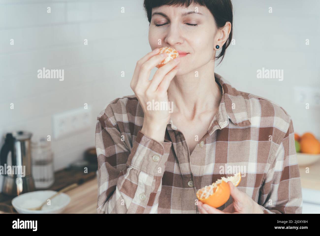 Anosmia, restore sense of smell. COVID-19 causes loss of smell. Happy woman sniffing citrus fruit Stock Photo