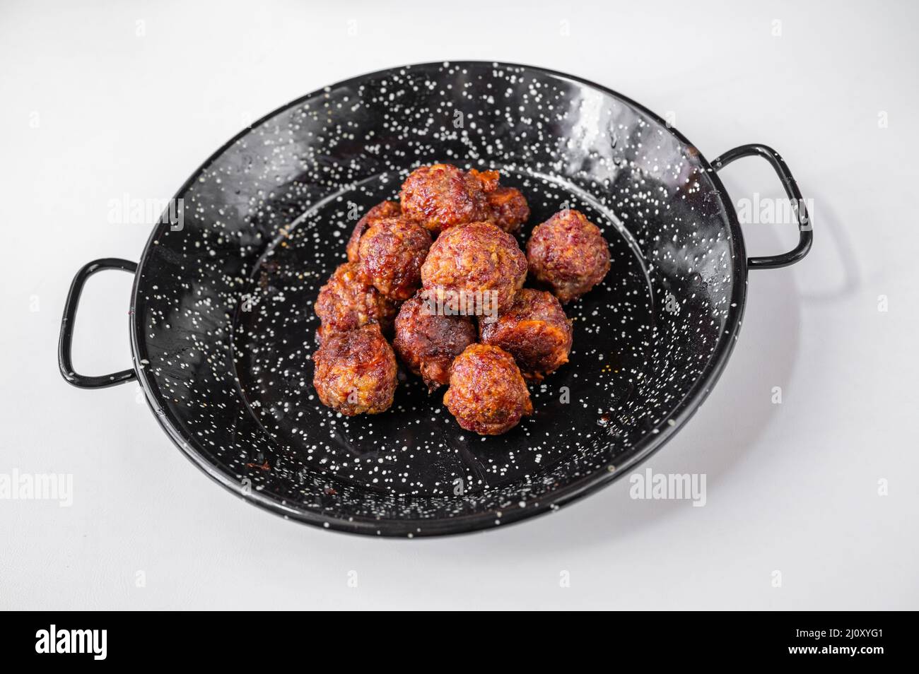 Baked meat ball with cheese on black rustic pan on white background, closeup. Stock Photo