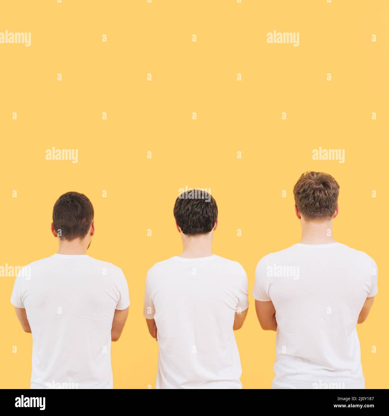 Rear view men white t shirt standing against yellow background. High quality photo Stock Photo