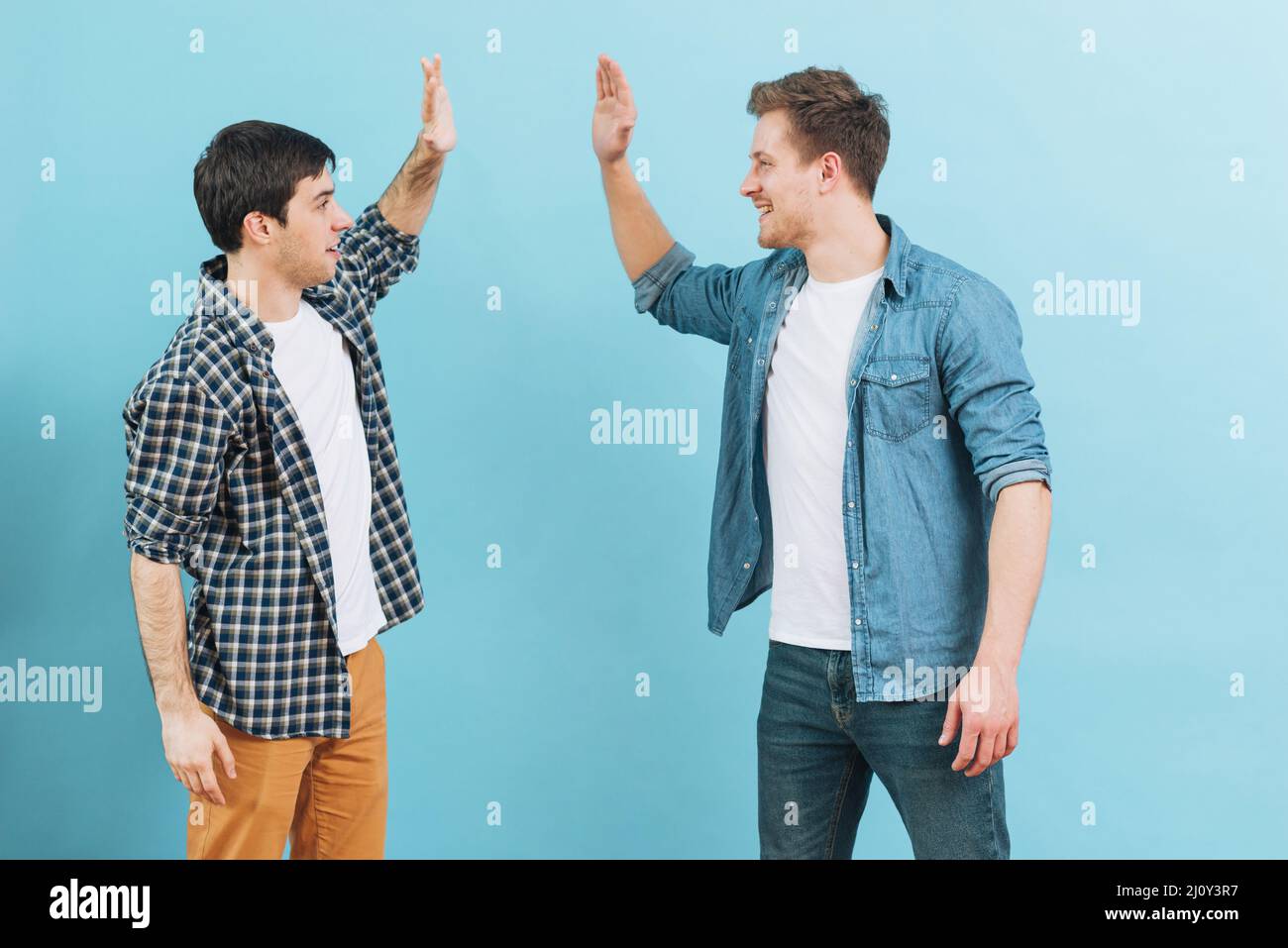 Young male friend giving high five against blue background. High quality photo Stock Photo