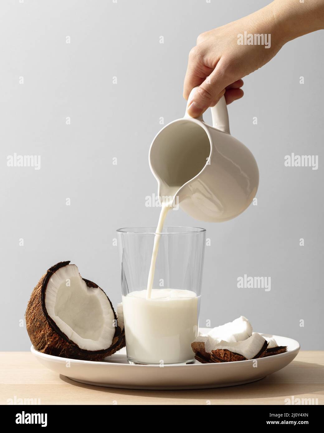 Front view hand pouring coconut milk glass. High quality photo Stock Photo