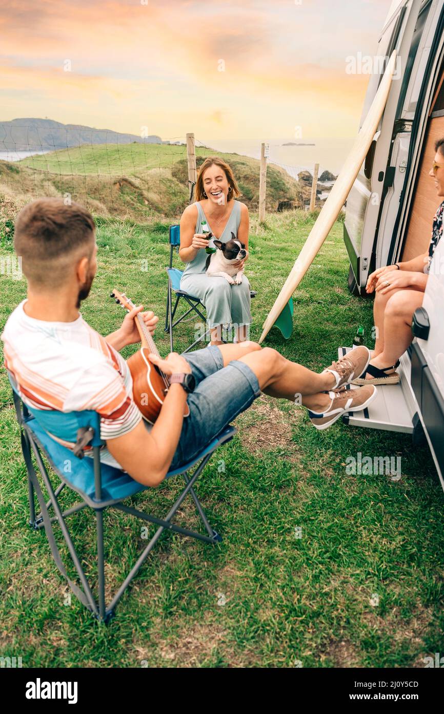 Friends with their dog drinking beer in front of their camper van Stock