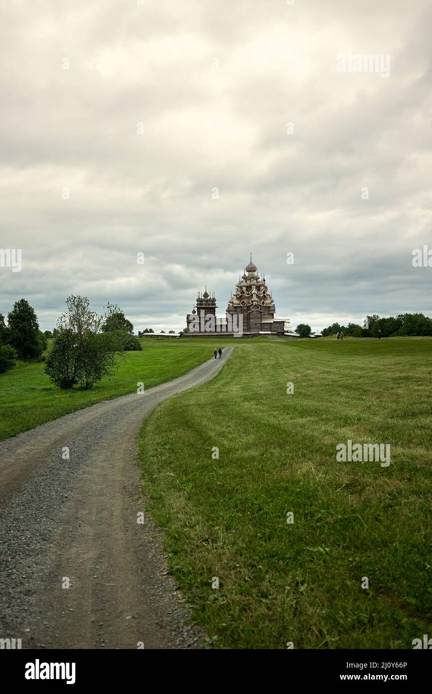 Gravel road leads through a field to a wooden Orthodox church on the island of Kizhi Karelia Stock Photo