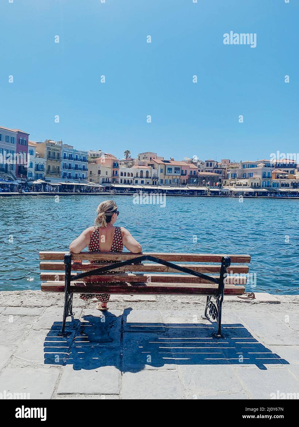 Young blond woman enjoying the beautiful views of the port of Chania in Venetian style. Stock Photo